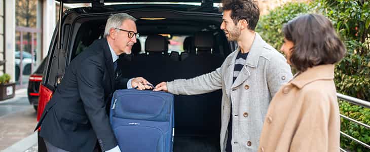 man putting luggage in back of van