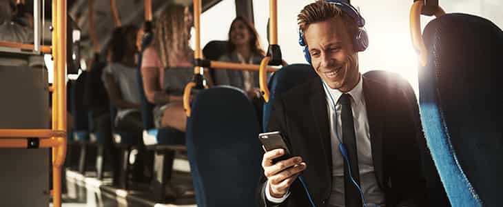 A businessman in a suit sitting in a black shuttle bus.